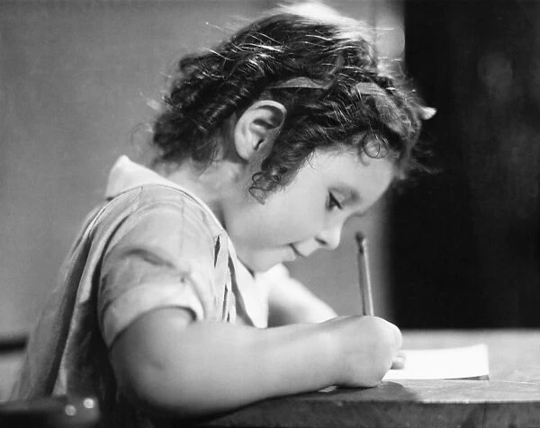 Girl (6-7) writing at table, (B&W)