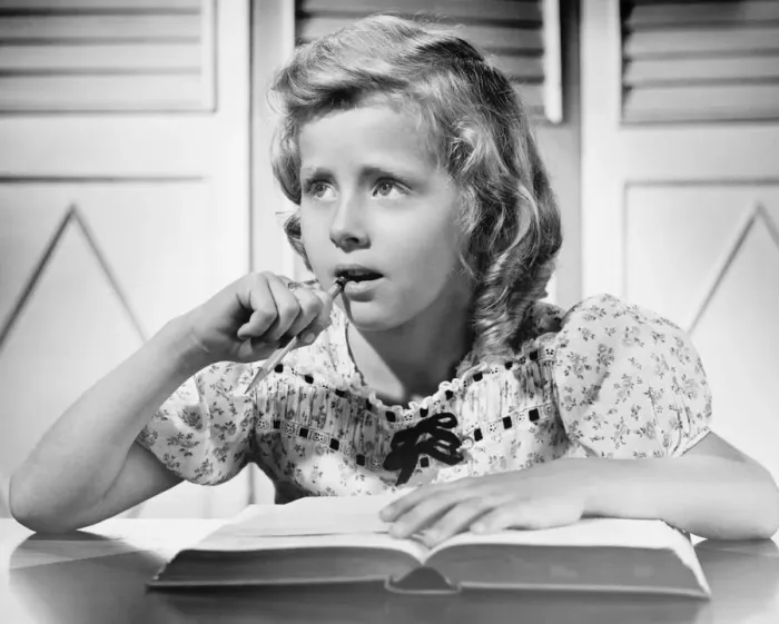 Framed Print : Girl (8-9) sitting at table, holding pencil in mouth, (B&W), close-up Framed Print : Girl (8-9) sitting at table, holding pencil in mouth, (B&W), close-up