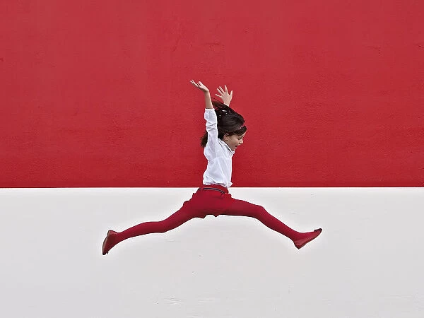 Girl jumping in air at red wall