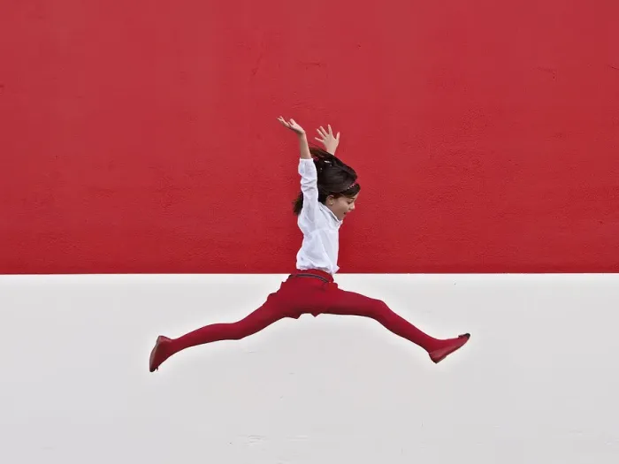 Framed Print : Girl jumping in air at red wall Framed Print : Girl jumping in air at red wall