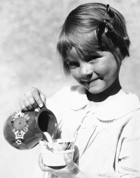 Framed Print : Girl poring milk from pitcher into cup Framed Print : Girl poring milk from pitcher into cup