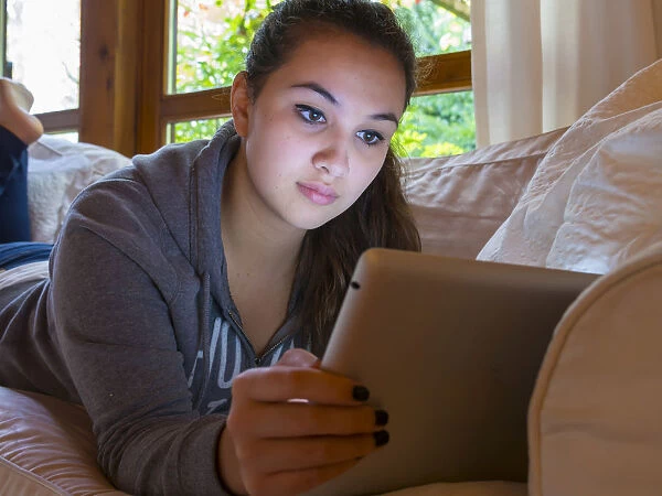 Girl reading on a tablet computer at home, Germany