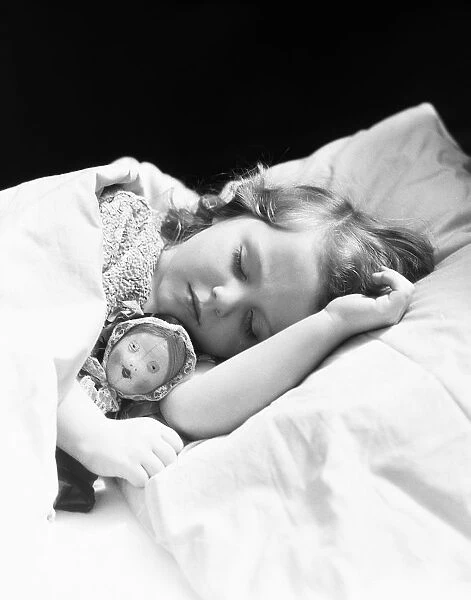 Girl sleeping, head on pillow, baby doll toy under arm