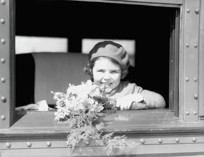 Framed Print : Girl on train, holding bouquet of flowers, wearing hat and jacket, smiling, looking out of window Framed Print : Girl on train, holding bouquet of flowers, wearing hat and jacket, smiling, looking out of window
