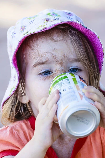 Girl, two years, face caked in sand, drinking from beverage can, Namibia