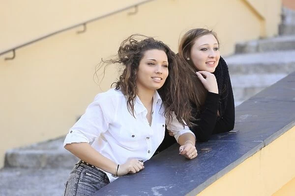 Two girlfriends, teenagers, leaning on the railing of a staircase, looking into the distance, Menton, Alpes-Maritimes, Provence-Alpes-Cote dAzur, France