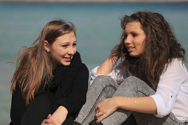 Two girlfriends, teenagers sitting on the beach, Menton, Alpes-Maritimes, Provence Alpes, France