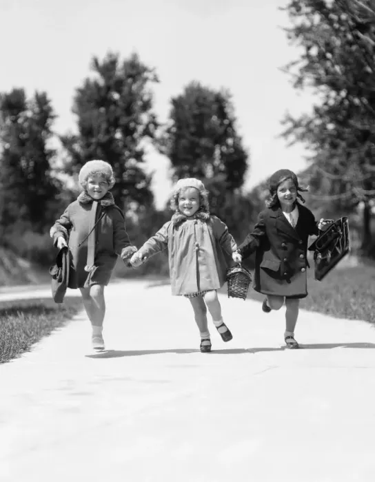Framed Print : Three girls running along suburban sidewalk wearing fall weather coats and hats