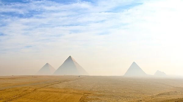 The Giza pyramids viewed from distance in morning haze and blue skies