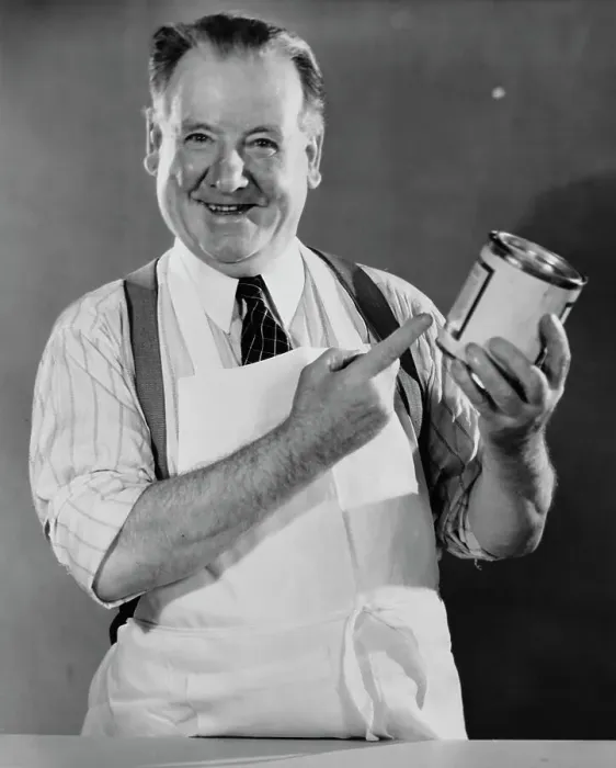 Framed Print : Grocer. A shopkeeper with a tin of food, circa 1940