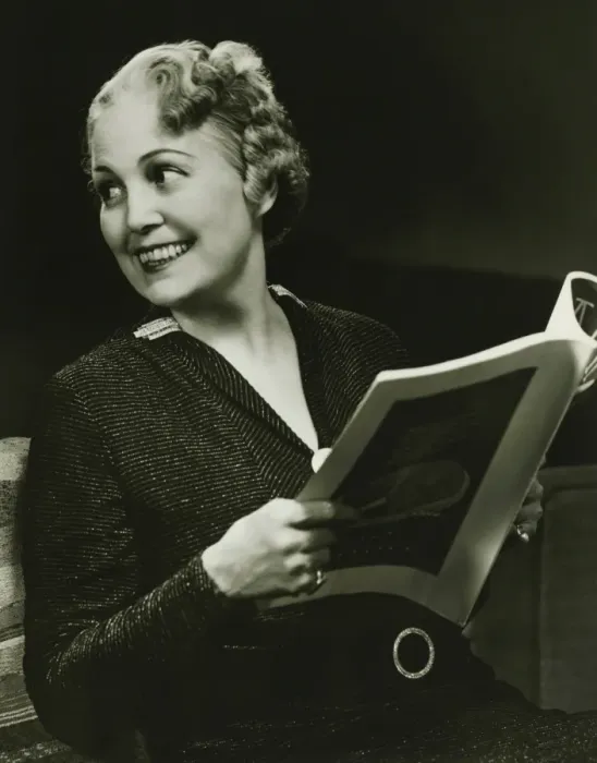 Framed Print : Well groomed mature woman holding fashion magazine in living room, (B&W), portrait