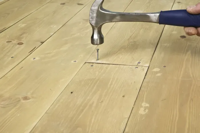Framed Print : Hammering a nail in to a floor board Framed Print : Hammering a nail in to a floor board