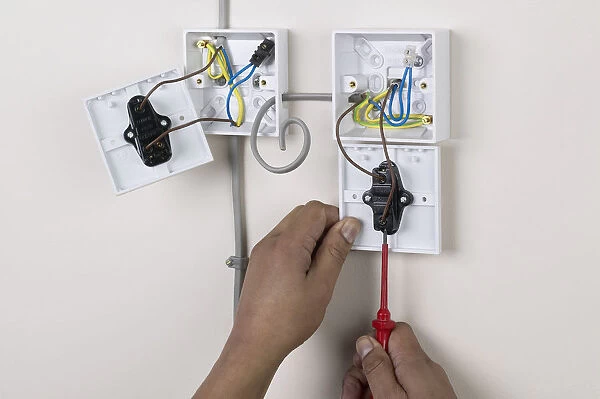 Hands holding screw driver to light switch, face plate off