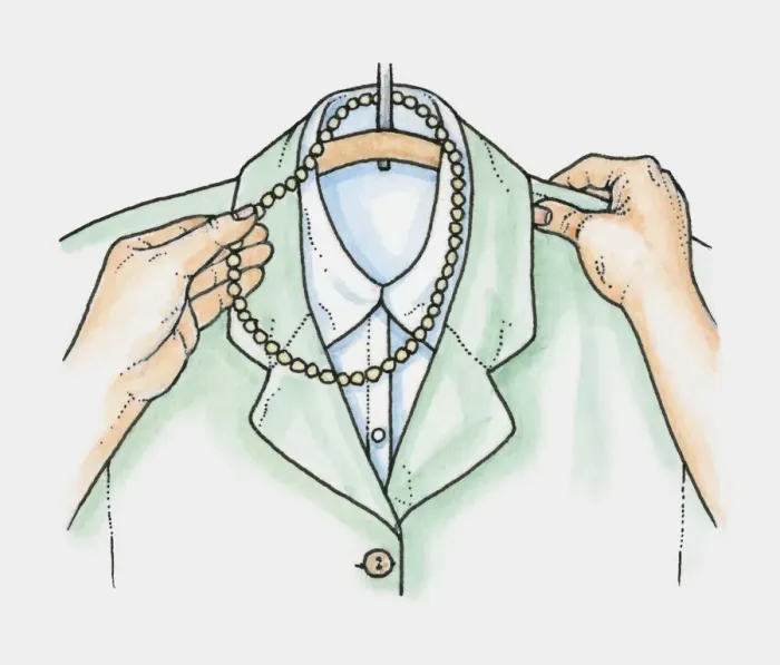 Framed Print : Hands placing necklace of beads over hanger holding jacket and blouse Framed Print : Hands placing necklace of beads over hanger holding jacket and blouse