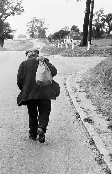 Hard Road. 25th July 1953: An old mand trudges up a road, sack on his back