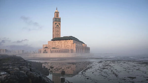 Hassan II Mosque at morning fog reflected on wetland along coastline