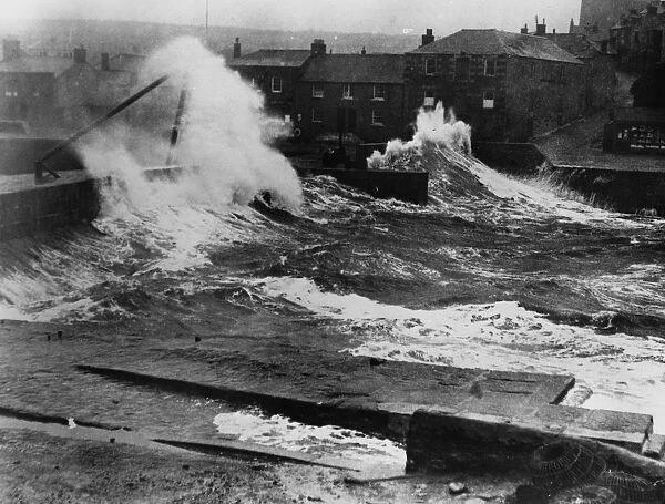 High Seas. circa 1925: Huge waves destroying the harbour wall in Porthleven, Cornwall