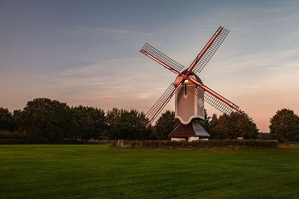 A historic windmill at sunset with a bench