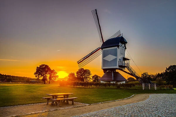 Historic windmill at sunset with a bench and stone path