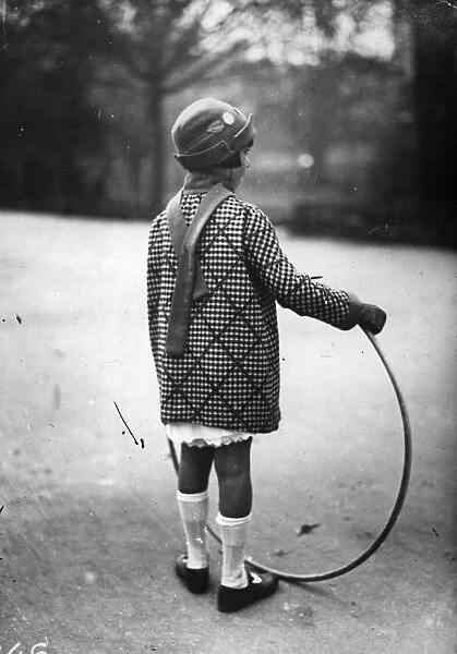 Hoop La. circa 1930: A girl plays with a hoop in a park