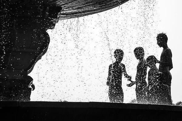 Too Hot. Many boys relax from hot air by water fountain in the Delhis public park