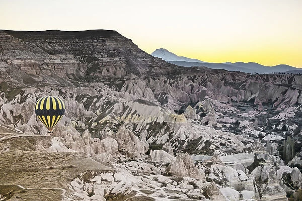 Hot air balloon flying over rock landscape at Cappadocia, Turkey