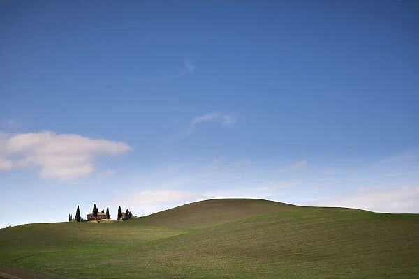 A house with cypress trees amoung landscape of Val d Orcia