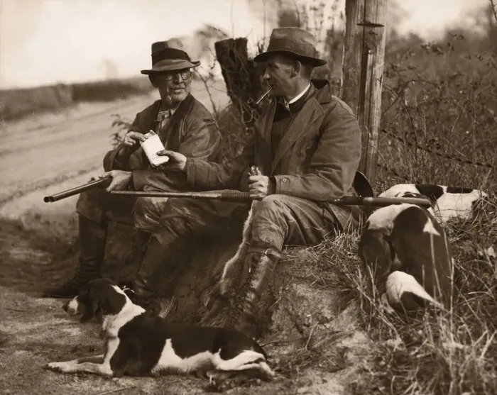 Framed Print : Two hunters with dogs sharing cigars (B&W sepia tone)
