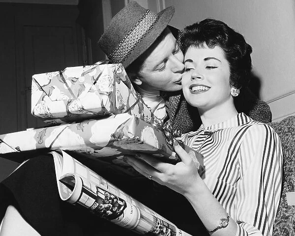 Husband kissing wife with armful of gifts