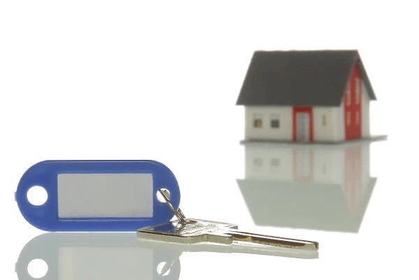 Key lying in front of a miniature house, symbolic image for property market