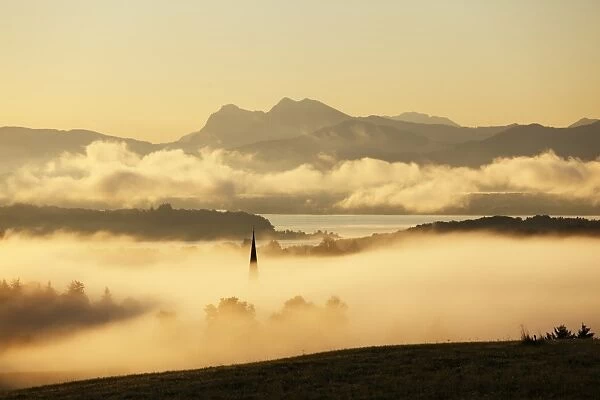 Lake Chiemsee and the church steeple of Greimharting as seen from Ratzinger Hoehe in the early morning, Chiemgau, Upper Bavaria, Bavaria, Germany, Europe