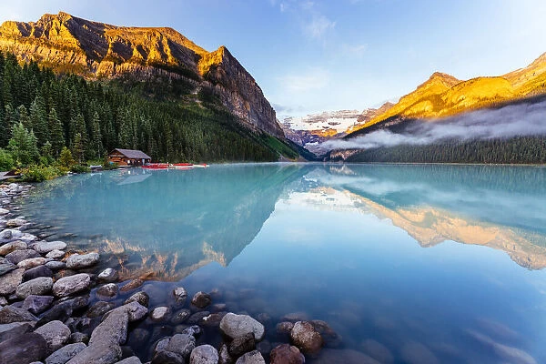 Lake Louise at sunrise, calm water and light on the mountain tops. Banff, Alberta, Canada