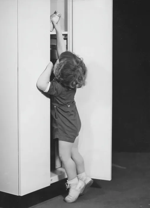 Framed Print : Larder. A young girl reaching up to grab a jar from the larder, circa 1940s