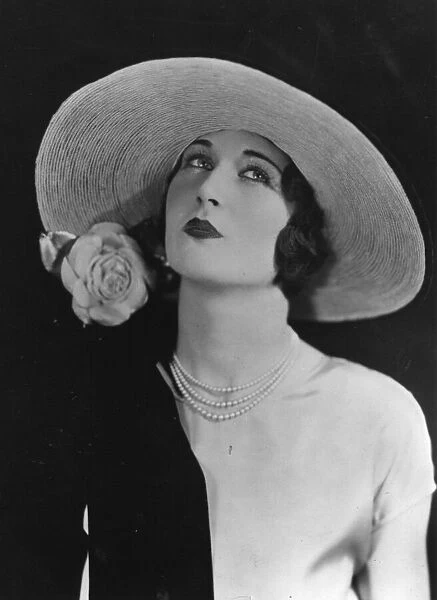 Large Hat. A woman wearing a wide brimmed hat with a rose