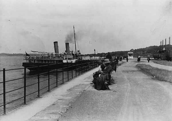 Lazy Days. circa 1912: A pleasure steamer berthed and people on a quayside bench
