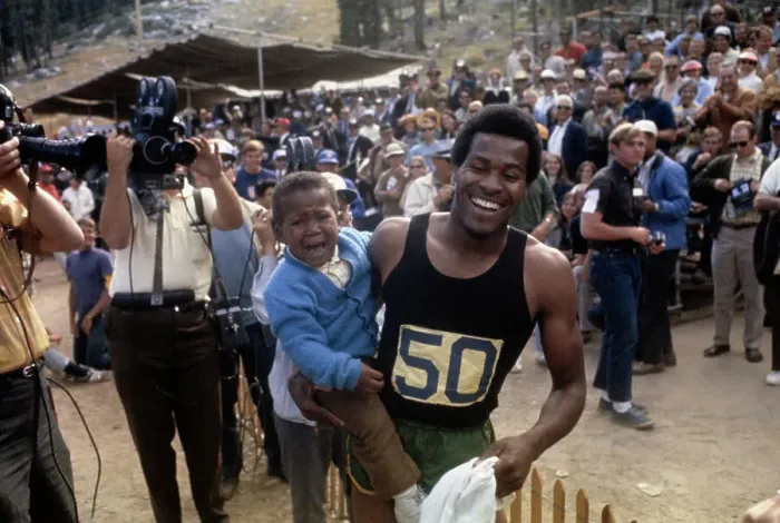 Framed Print : Lee Evans. American sprinter Lee Evans (1947 - 2021) holding his son Keith Framed Print : Lee Evans. American sprinter Lee Evans (1947 - 2021) holding his son Keith