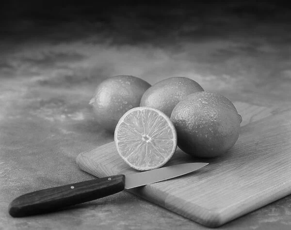 Lemon whole and half cut on chopping board with knife