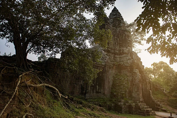 last light at main gate of angkor thom and Ruin wall and root