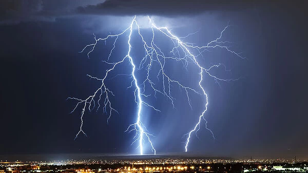 Lightning and storm. Lightning bolt on horizon, over city lights. Multiple arcs