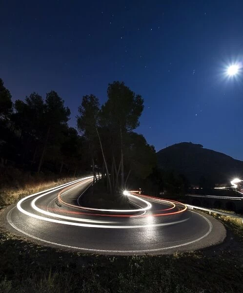 Lights of vehicles in movement circulating along a carretera with curves very closed in the moonlight