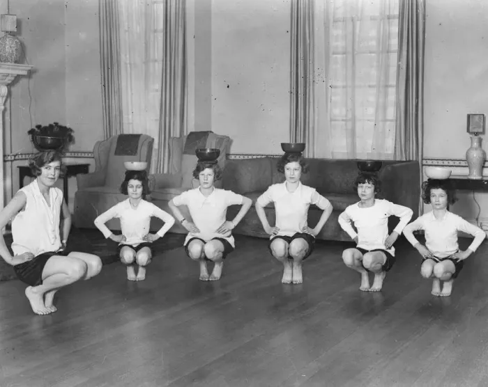 Framed Print : Line of girls (7-12) exercising with bowls on heads (B&W) Framed Print : Line of girls (7-12) exercising with bowls on heads (B&W)