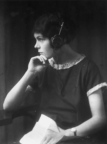 Listener. circa 1930: A girl wearing headphones