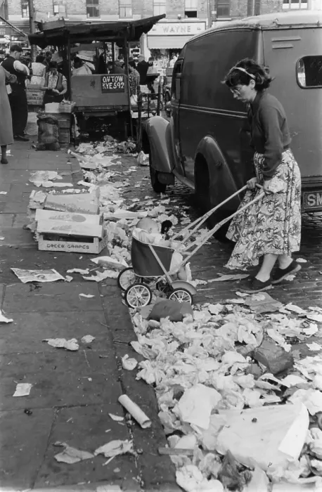 Framed Print : Litter. A woman propelling her baby in a pushchair through the piles of