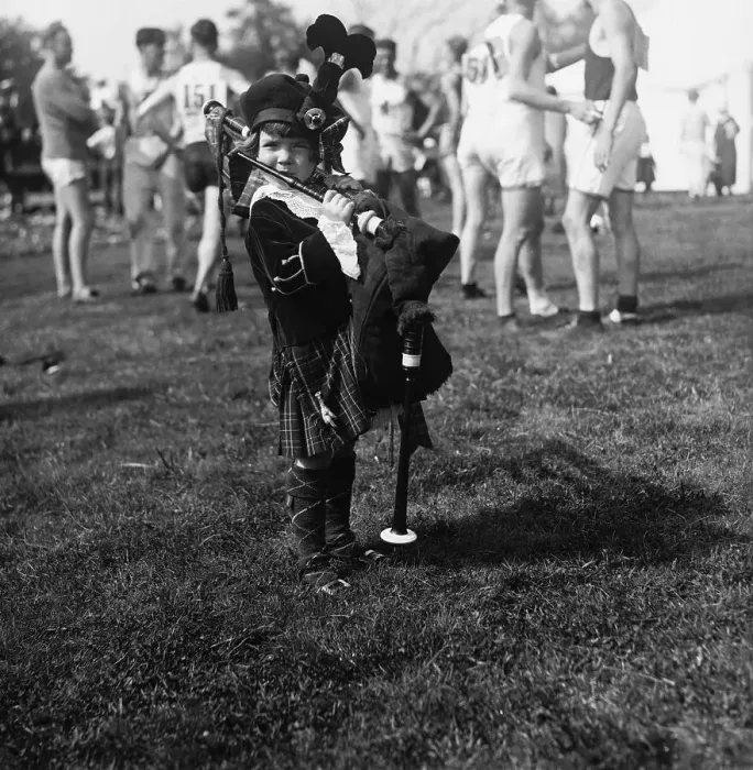 Framed Print : Little Girl (2-3 years) Playing Bagpipes, football players in background. Boston, Massachusetts, USA. August 04, 1925 Framed Print : Little Girl (2-3 years) Playing Bagpipes, football players in background. Boston, Massachusetts, USA. August 04, 1925
