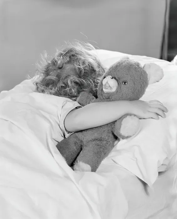 Framed Print : Little girl asleep in bed, with arm around teddy bear