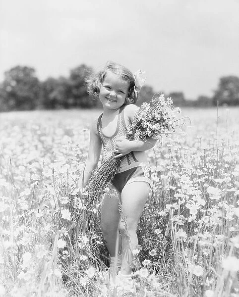 Little girl picking daisy bouquet in summer meadow