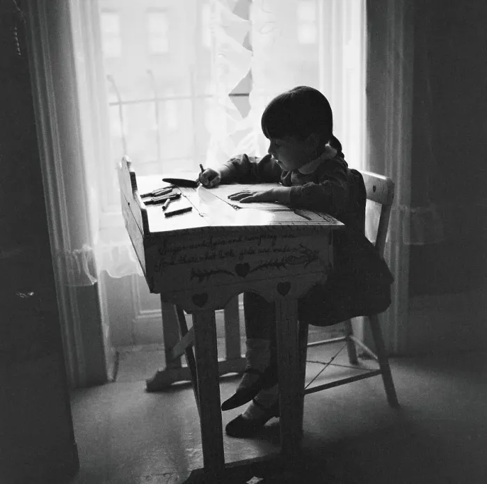 Framed Print : Little girl silhouetted at window, sitting at desk, studying, urban view out of window Framed Print : Little girl silhouetted at window, sitting at desk, studying, urban view out of window