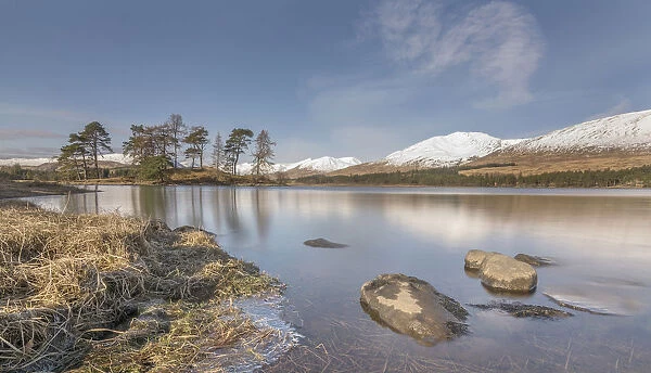 Loch Tula. Scottish Loch with rocks and trees with snowy mountains