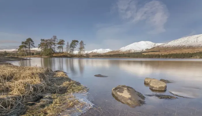 Framed Print : Loch Tula. Scottish Loch with rocks and trees with snowy mountains