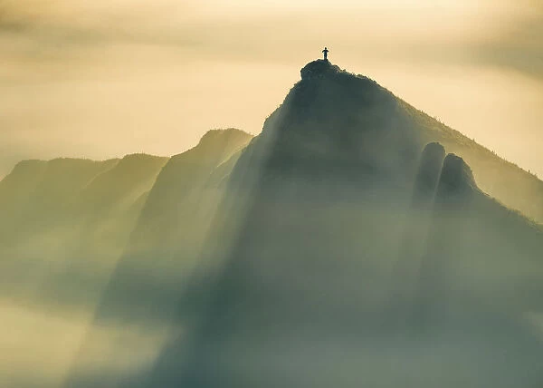 A Lone man stands on a jagged hill in misty conditions at sunrise, English Peak District. UK